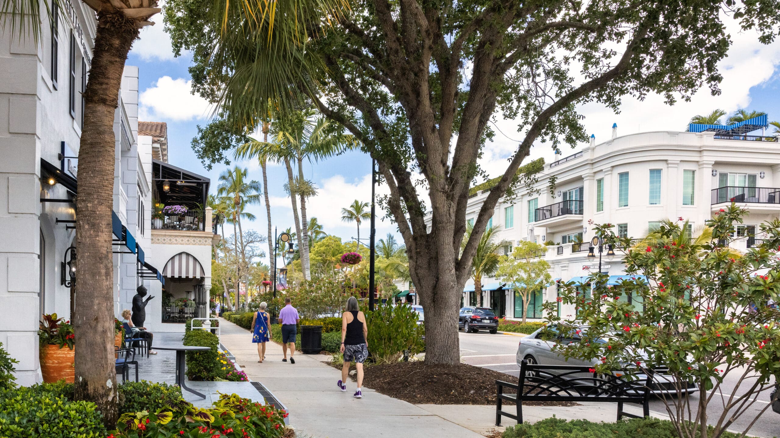 Pedestrian-friendly street in Downtown Naples Florida with palm-lined sidewalks, upscale shops, and Mediterranean-style buildings